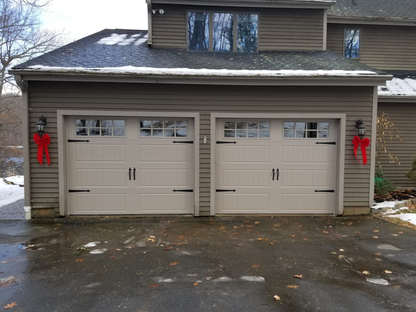Almond color carriage garage door with black spade-shaped handles and hinges 
